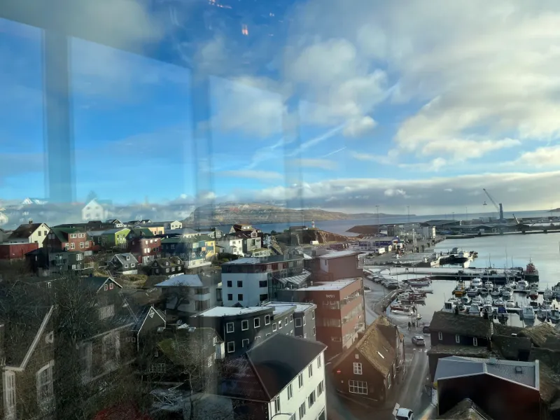 Udsigt over en havn og farverige bygninger set gennem et vindue på en solrig dag.