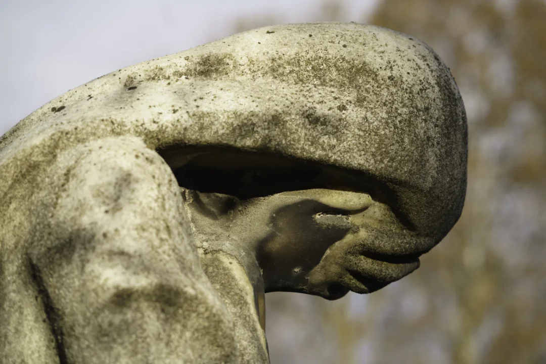 Statue cimitero med hovedet i hænderne