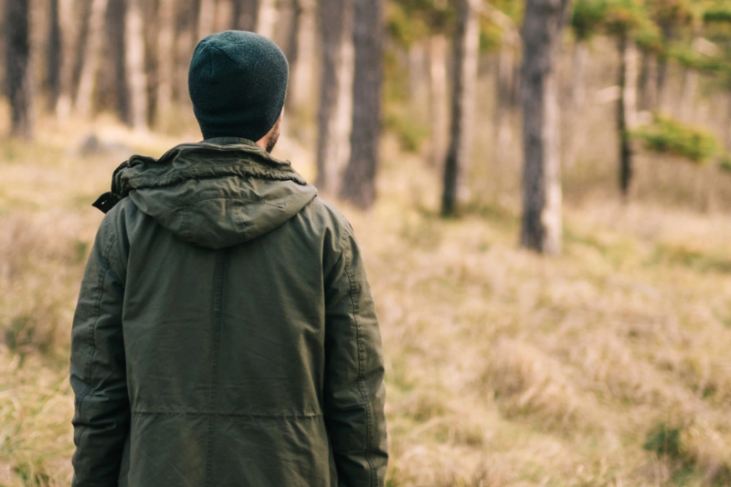 Mand med ryggen til i en skov