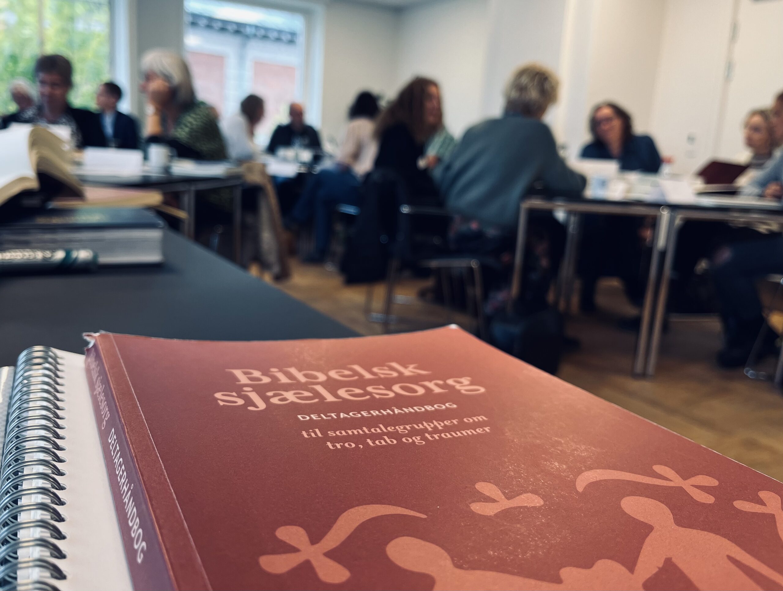 En kvinde og en mand sidder ned. Foran dem er der en masse papirer. Kvinden holder ét stykke papir i hendes hånd.