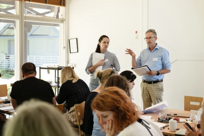 To oplægsholdere står foran deltagere ved et kursus eller seminar og faciliterer gruppearbejde.